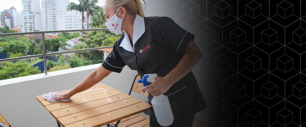 Foto de uma mulher realizando o serviço de limpeza em uma mesa de madeira